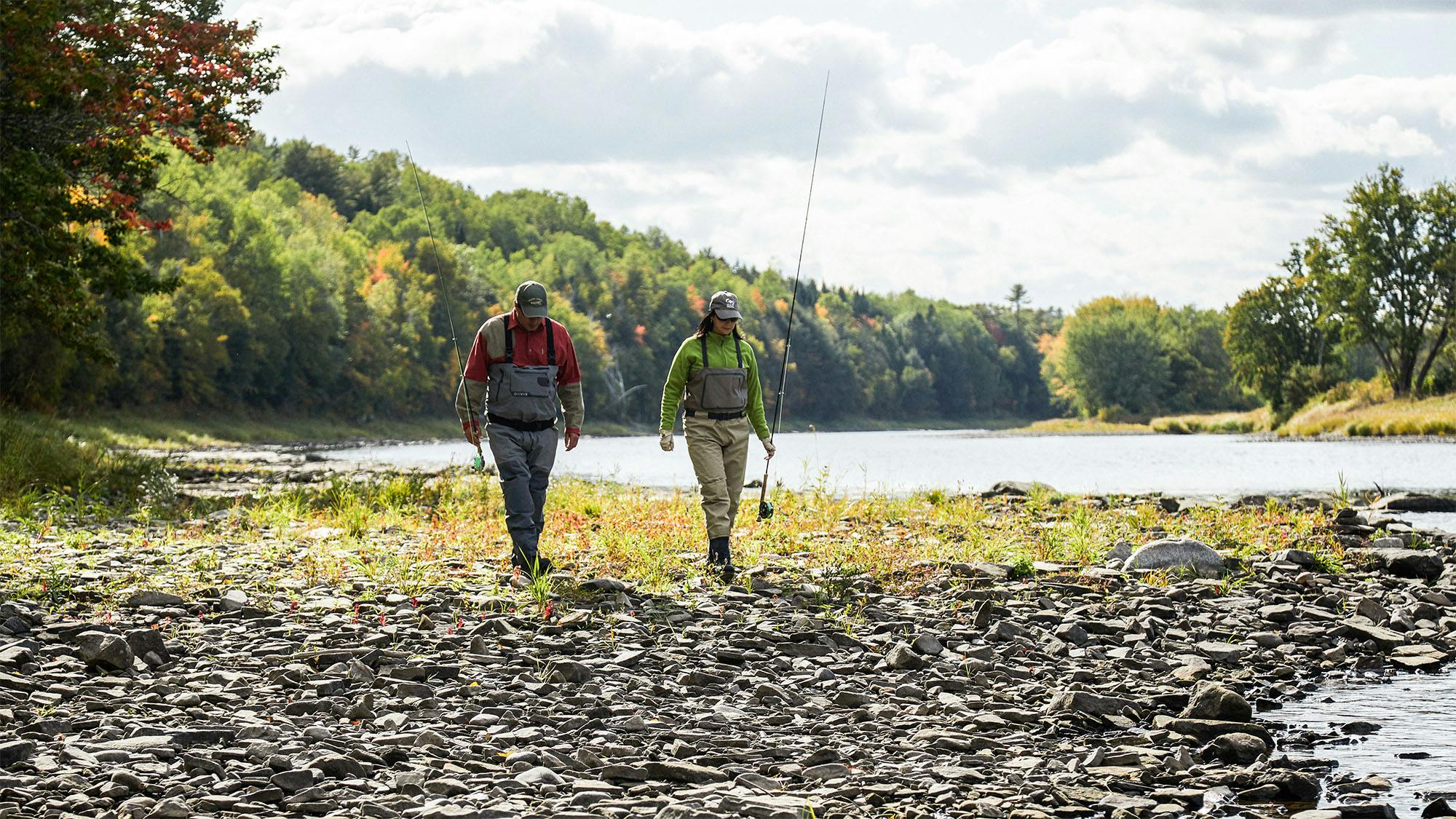 Two people walking towards the camera holding fishing rods